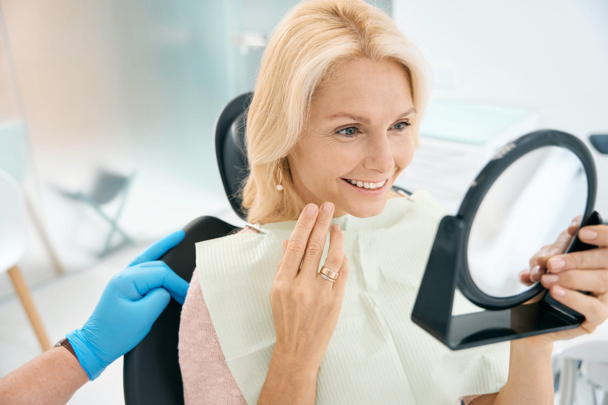 Close up portrait of pretty Caucasian female enjoying her beautiful smile after the dentistry treatment in medicine center